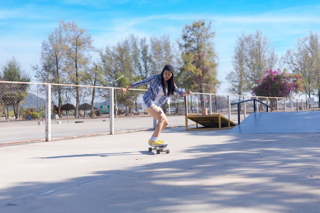 Jovem mulher asiática andando de skate da velha escola no skatepark