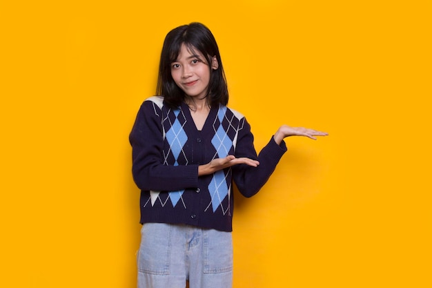 jovem mulher asiática apontando com os dedos para diferentes direções isoladas em fundo amarelo