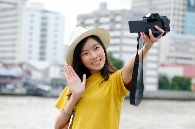 Jovem mulher asiática bonita no estilo casual, usando a câmera para selfie