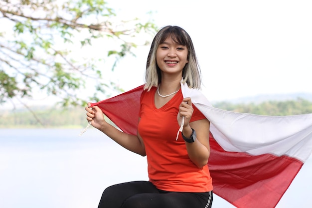 Jovem mulher asiática carregando bandeira indonésia