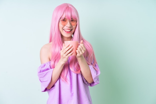 Jovem mulher asiática com cabelo rosa posando sobre fundo verde