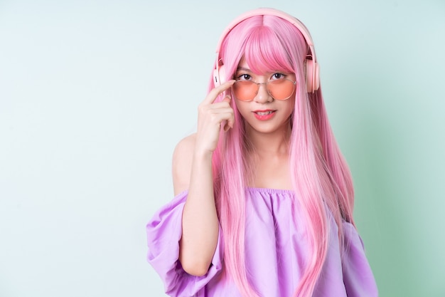 Jovem mulher asiática com cabelo rosa posando sobre fundo verde