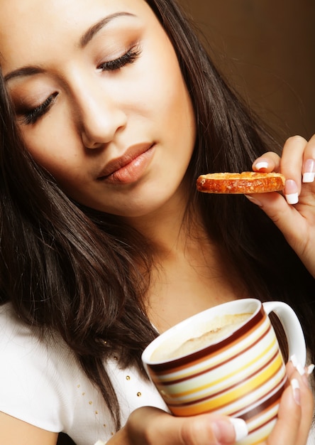 Foto jovem mulher asiática com café e biscoitos.