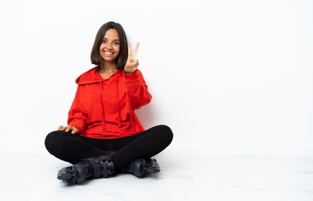 Jovem mulher asiática com patins no chão sorrindo e mostrando sinal de vitória