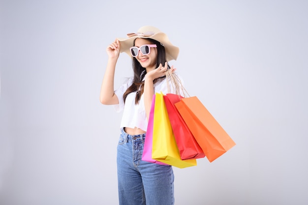 Jovem mulher asiática com sacolas de compras e chapéu de palha
