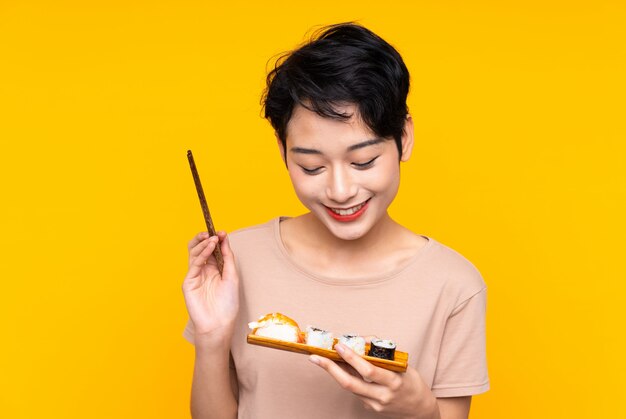 Foto jovem mulher asiática com sushi com expressão feliz