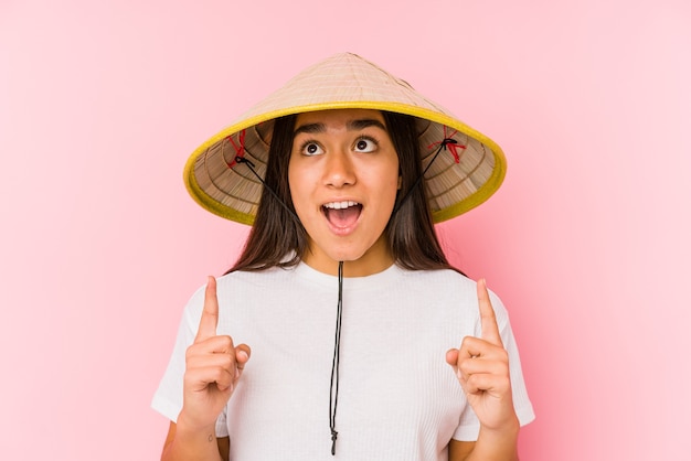 Jovem mulher asiática com um chapéu vietnamita isolado jovem mulher asiática com um chapéu vietnamita de cabeça aberta com a boca aberta.