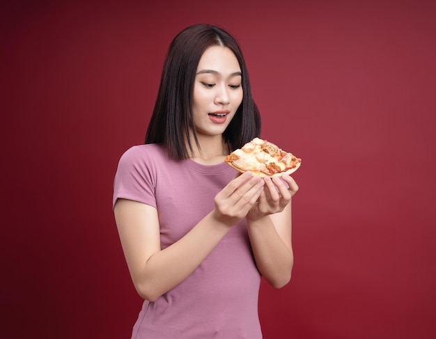 Jovem mulher asiática comendo pizza no fundo