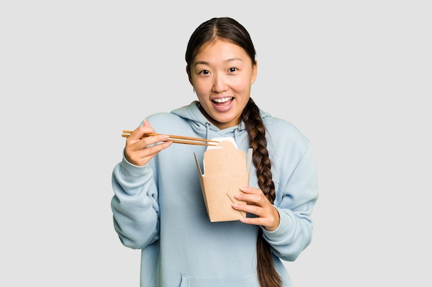 Jovem mulher asiática comendo ramen para viagem isolado