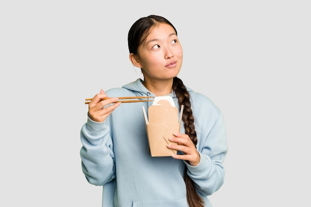 Jovem mulher asiática comendo ramen para viagem isolado