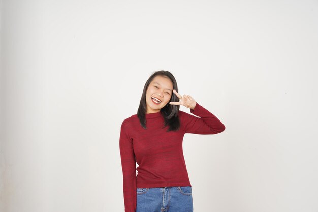 Jovem mulher asiática de camisa vermelha sorrindo e mostrando sinal de paz ou vitória mostrando isolado em fundo branco