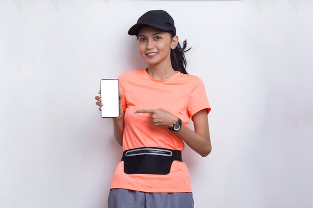 Jovem mulher asiática desportiva demonstrando telefone celular em fundo branco