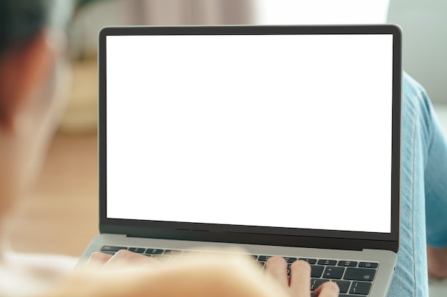 Foto jovem mulher asiática digitando o teclado do computador laptop com tela branca em branco no sofá. trabalhar em casa, relaxar, fazer compras online, conceito de comunicação e tecnologia