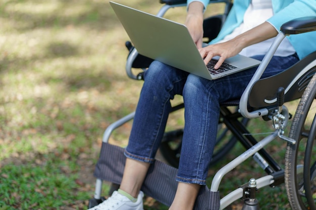 Jovem mulher asiática em cadeira de rodas trabalhando com laptop