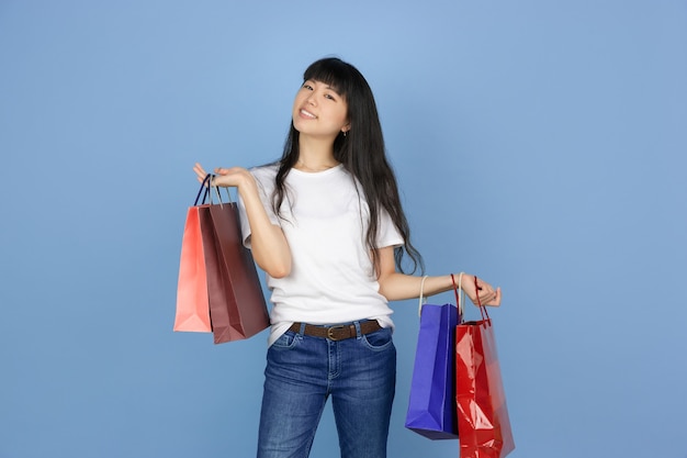 Jovem mulher asiática em fundo azul, compras