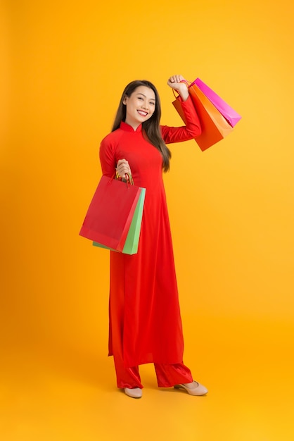 Jovem mulher asiática em um vestido tradicional ao dai comprando, segurando um saco de papel com as mãos, celebrando o Ano Novo Lunar ou o festival da primavera