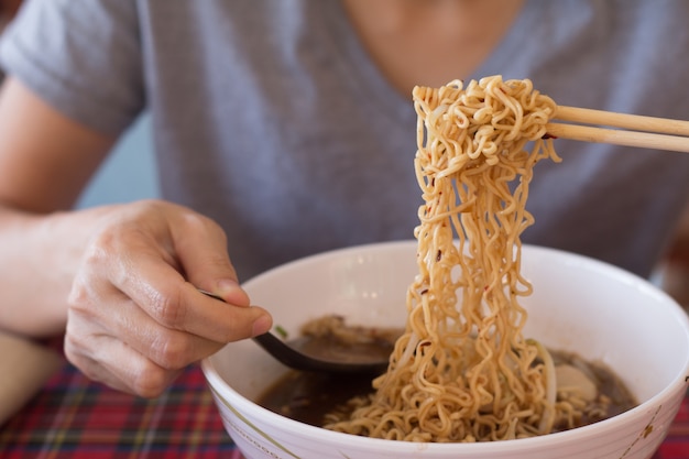 Jovem mulher asiática está comendo macarrão