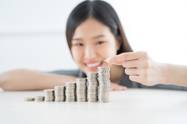 Foto jovem mulher asiática fazendo pilha de moedas