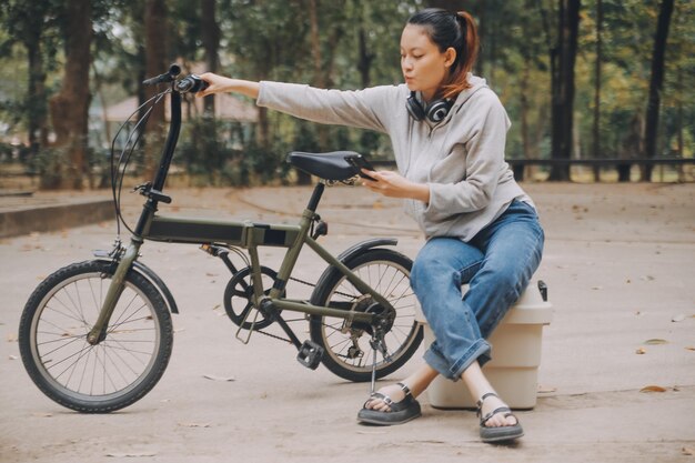 Foto jovem mulher asiática feliz caminhando e andando de bicicleta na rua do parque da cidade sorrindo usando bicicleta de transporte ecológico conceito de estilo de vida das pessoas.