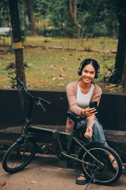 Jovem mulher asiática feliz enquanto andava de bicicleta em um parque da cidade Ela sorriu usando a bicicleta de transporte conceito ecológico