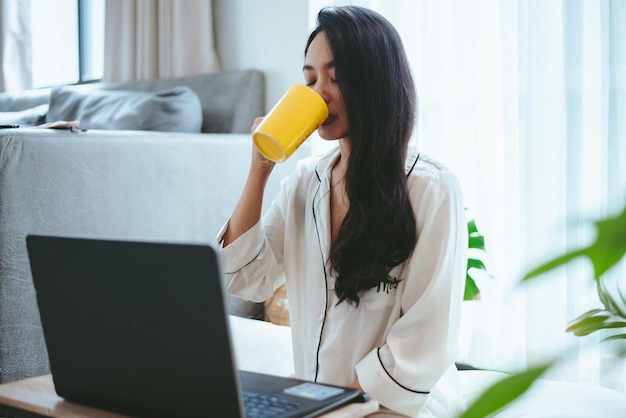 Jovem mulher asiática freelance, trabalhando, trabalhando em um laptop em casa, trabalhando em casa.