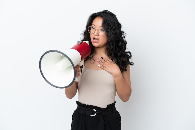 Foto jovem mulher asiática isolada no fundo branco gritando em um megafone com expressão de surpresa