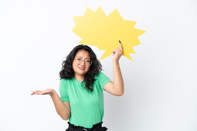 Foto jovem mulher asiática isolada no fundo branco segurando um balão de fala vazio e com expressão de frustração