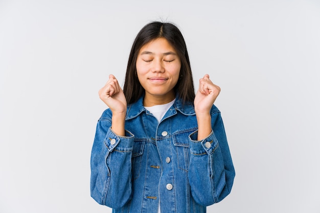 Jovem mulher asiática, levantando o punho, sentindo-se feliz e bem sucedido. Conceito de vitória