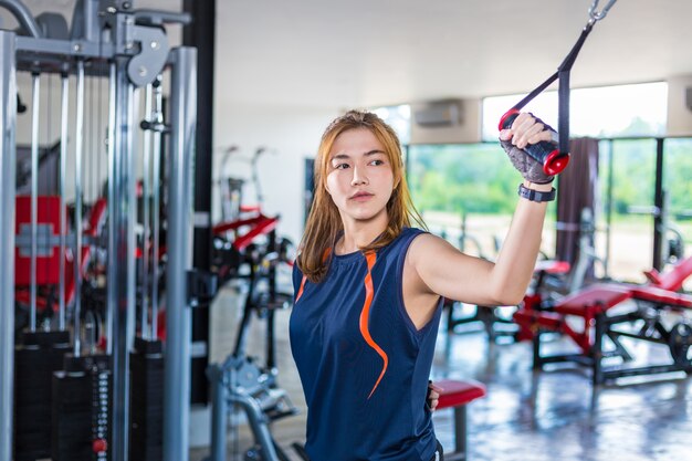 Jovem mulher asiática malhando e fazendo treinamento físico em uma academia local