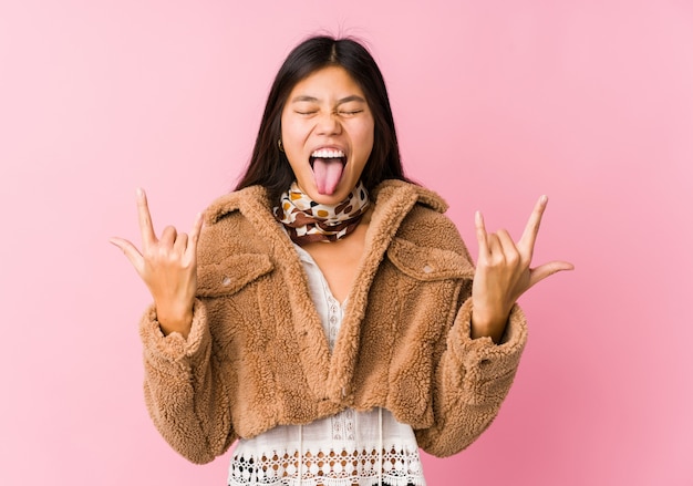 Jovem mulher asiática mostrando o gesto do rock com os dedos