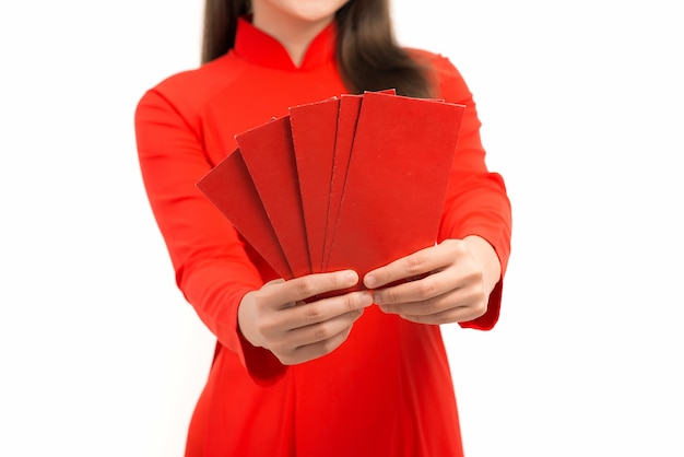 Jovem mulher asiática mostrando um envelope vermelho para o ano novo lunar enquanto usava Ao Dai sobre branco.