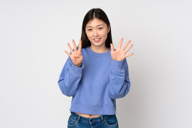 Jovem mulher asiática na parede, contando nove com os dedos