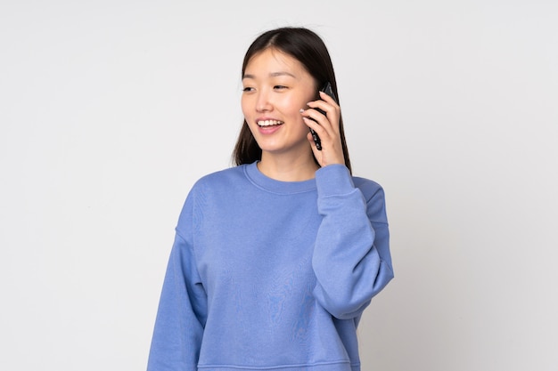 Jovem mulher asiática na parede, mantendo uma conversa com o telefone móvel
