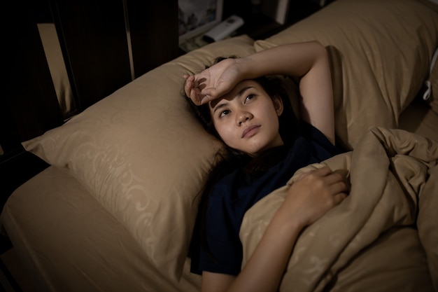 Jovem mulher asiática não consegue dormir a insônia tarde da noite. Não consigo dormir. Apnéia do sono ou estresse. Conceito de distúrbio do sono.