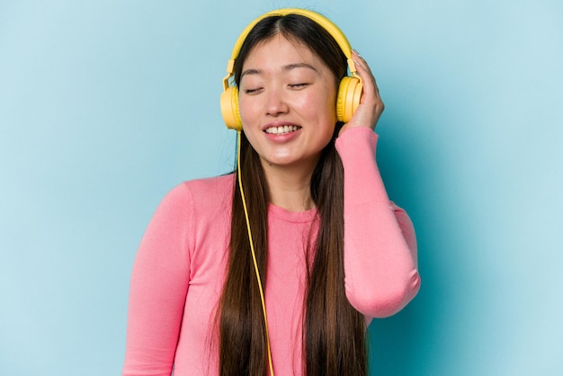 Jovem mulher asiática ouvindo música isolada em fundo azul