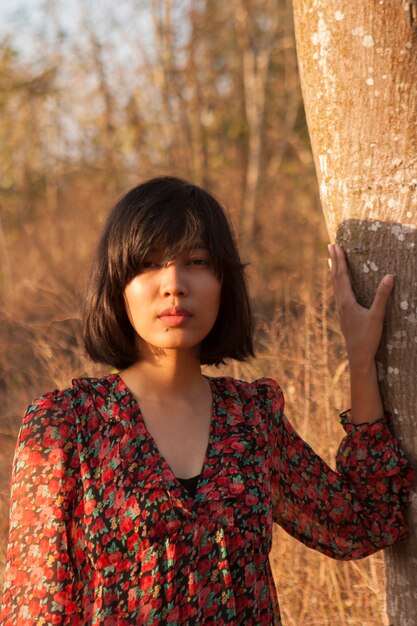 Jovem mulher asiática posando ao pôr do sol na natureza