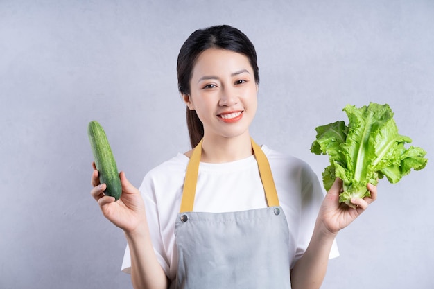 Jovem mulher asiática segurando legumes no fundo