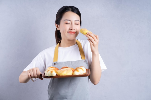 Jovem mulher asiática segurando pão no fundo