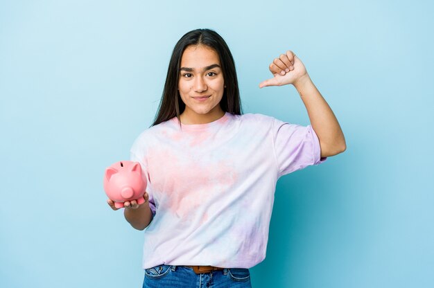 Jovem mulher asiática segurando um banco rosa sobre uma parede isolada se sente orgulhosa e autoconfiante, exemplo a seguir