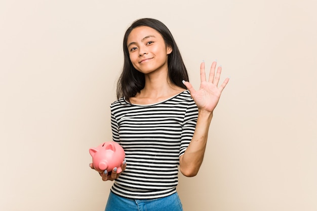 Jovem mulher asiática segurando um cofrinho