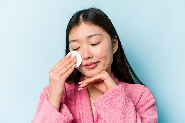 Jovem mulher asiática segurando um disco facial isolado no fundo rosa