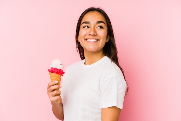 Jovem mulher asiática segurando um sorvete, olhando de lado sorrindo, alegre e agradável.