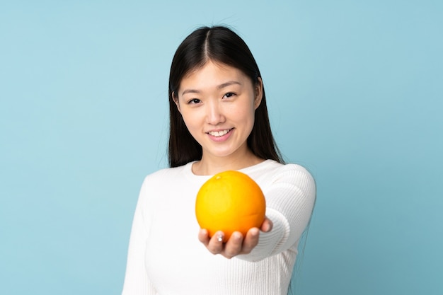 Jovem mulher asiática segurando uma laranja