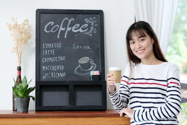 Jovem, mulher asiática, segurando uma xícara de café