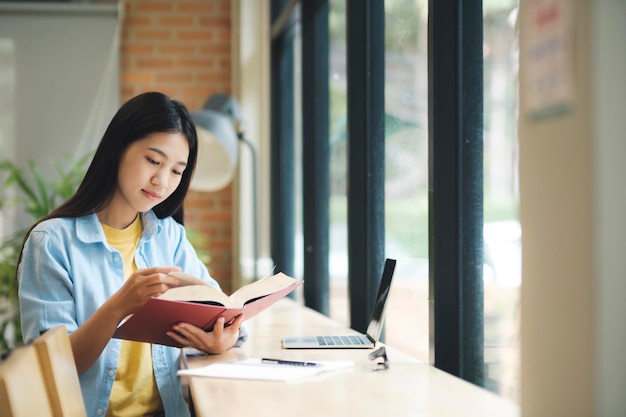 Jovem mulher asiática sentada e lendo livro