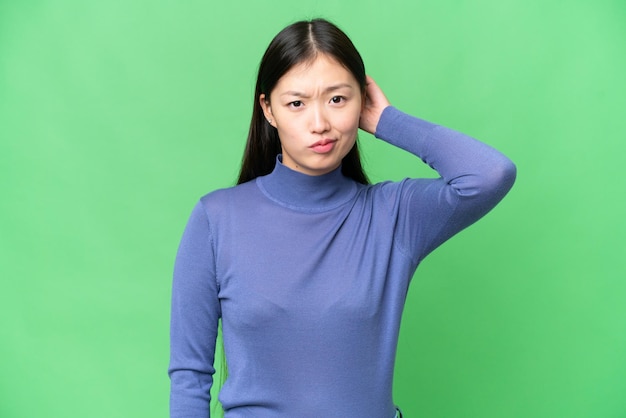 Jovem mulher asiática sobre fundo croma isolado tendo dúvidas