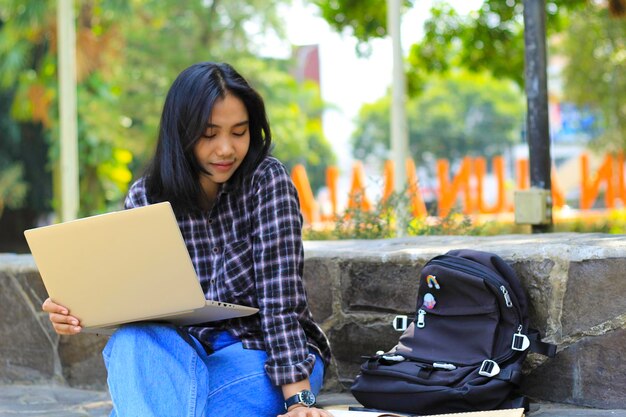 jovem mulher asiática sorridente usando laptop e escrevendo caderno estudante asiático alegre assistindo webinar