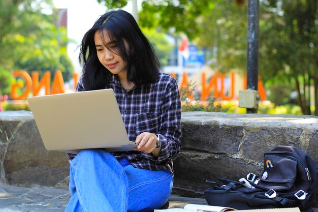 jovem mulher asiática sorridente usando laptop e escrevendo caderno estudante asiático alegre assistindo webinar