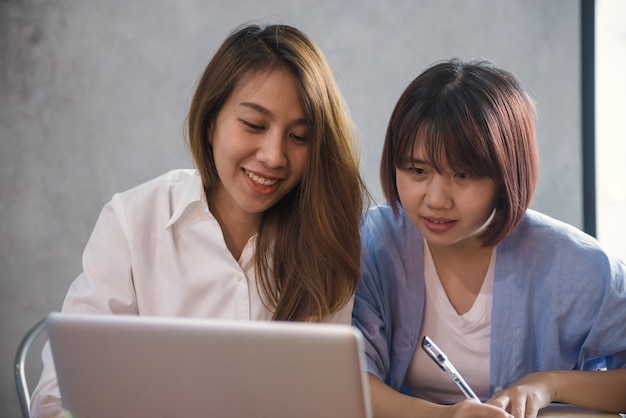 Jovem, mulher asiática trabalhando com computação laptop com rosto sorridente em estilo de vida casual