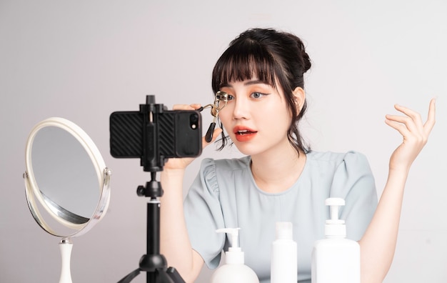 Jovem mulher asiática transmitindo ao vivo para professora de maquiagem online